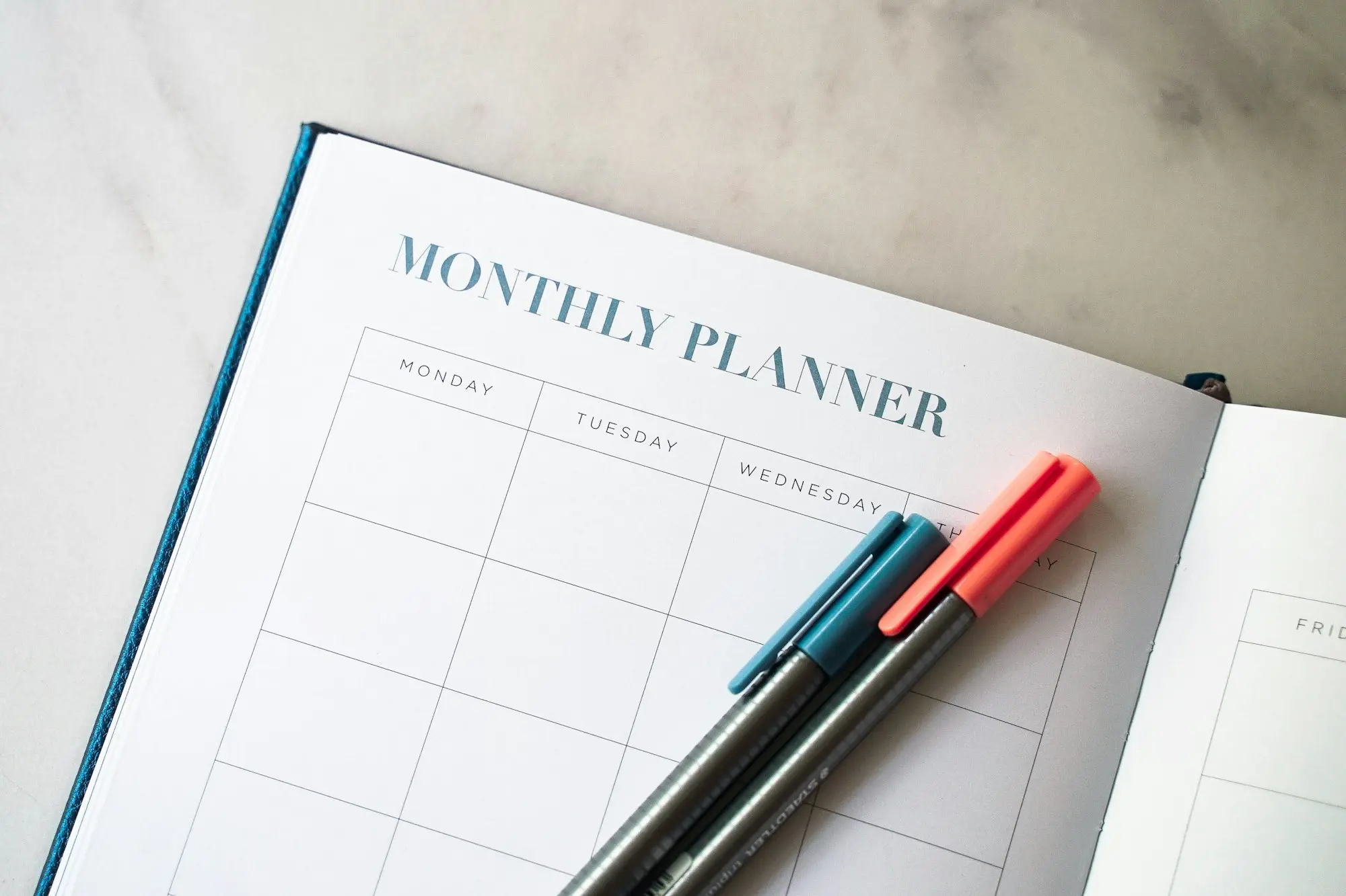 Monthly planner and pens on a desk for planning around EOFY